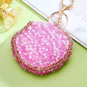 Close-up detail of luxury rhinestone pink shell keychain cosmetic mirror, sparkling bag pendant.