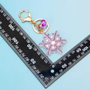 Close-up detail shot of the sparkling rhinestone snowflake keychain with metal clasp.