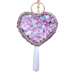 Detailed view of the sparkling heart-shaped sequin mirror keychain with rhinestone trim.