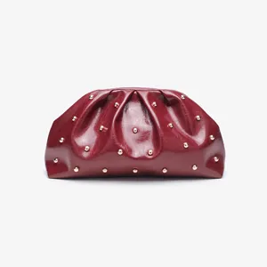 Dettaglio pochette plissettata bordeaux, pelle morbida con borchie metalliche.
