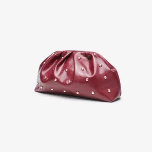 Vista di dettaglio della pochette plissettata rosso vino con borchie dorate, pelle.