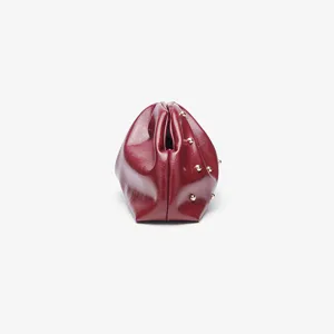 Dettaglio di una pochette plissé in ecopelle rossa con borchie metalliche e chiusura.
