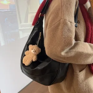 Black slouchy hobo shoulder bag for women with cute plush bear keychain and soft dumpling design.
