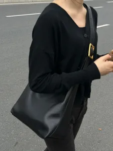 Detailed view of a stylish black slouchy shoulder bag with a wide strap and gold buckle.