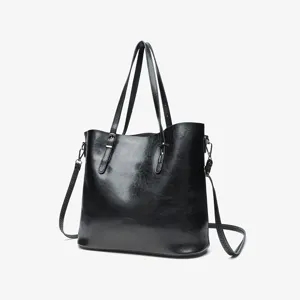 Detail shot of the classic black oil-wax leather tote bag showing smooth texture and handles.