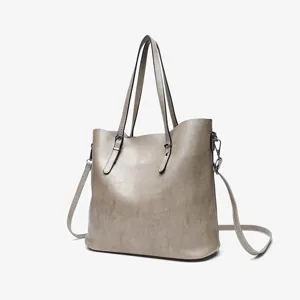Grey oil-wax leather tote bag detail, featuring dual top handles and long crossbody strap.