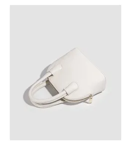 Detailed view of the white minimalist dome handbag showing smooth leather texture.