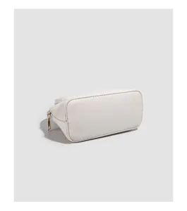 Detail view of a minimalist white shell bag showing quality PU leather texture and gold zipper.