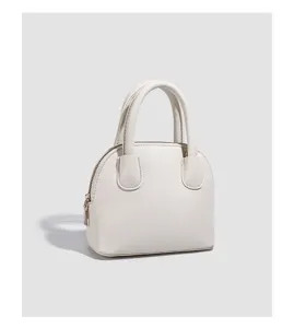 Minimalist white dome handbag detail, elegant top-handle crossbody bag for daily wear.