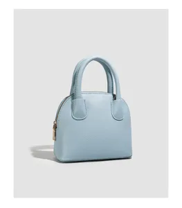 Light blue leather dome handbag detail, showing classic top handles and metal hardware.