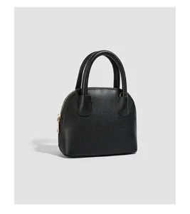 Close-up detail view of the black textured dome handbag showcasing premium golden zipper.