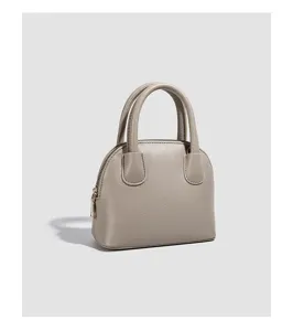 Grey leather dome crossbody shell handbag detail showing texture and zipper closure.