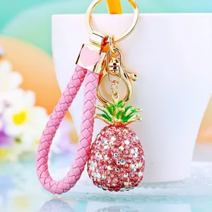 Close-up of the sparkling rhinestone pineapple keychain with pink braided strap and cute charm.