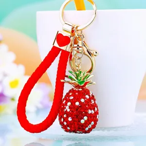 Close-up detail of the sparkling red rhinestone pineapple keychain pendant with golden hardware.