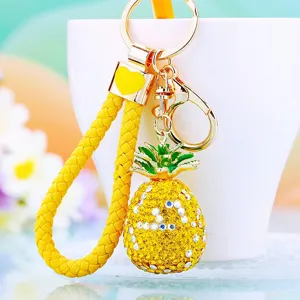Close-up of shiny rhinestone pineapple keychain with yellow braided strap and metal clasp.