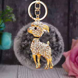 Close-up of the sparkling rhinestone goat keychain with fluffy gray plush ball and gold hook.