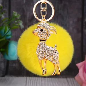 Detailed shot of sparkling rhinestone ram keychain with fluffy yellow pom pom and gold hardware.