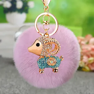 Detailed shot of cute crystal ram metal keychain with soft purple plush pom pom bag pendant.