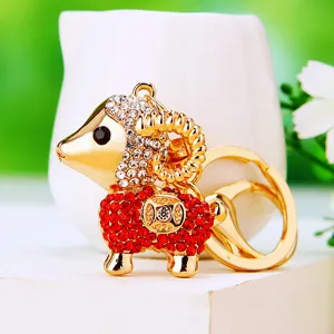 Detailed close-up of a glittering gold-plated sheep keychain with red and white crystal rhinestones.