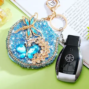Detailed view of the sparkling rhinestone butterfly and dragonfly makeup mirror keychain.