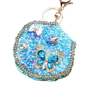 Detailed view of a glittering blue rhinestone cosmetic mirror keychain with butterfly.