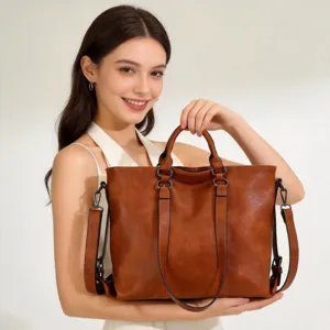 Close-up view of a brown soft leather tote bag held by a model, showcasing texture and handle.