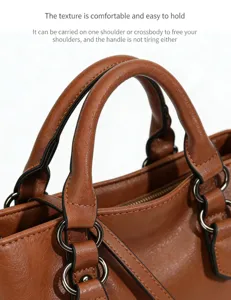 Detailed shot of brown soft leather handbag handle, featuring delicate metal rings and stitching.