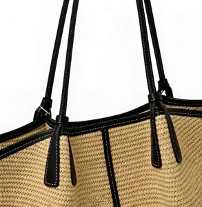 Nahaufnahme Detail der gewebten Stroh Strandtasche mit schwarzen Ledergriffen und Textur.