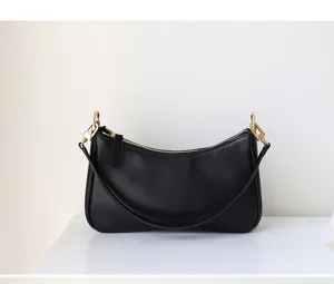 Nahaufnahme der schwarzen minimalistischen Schultertasche mit schicken goldenen Beschlägen.