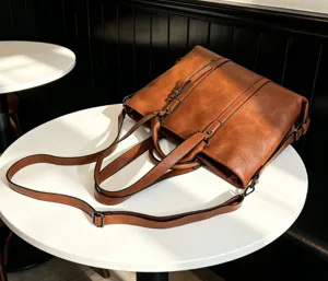 Detail view of the brown soft leather tote bag, showing shoulder straps and large capacity.