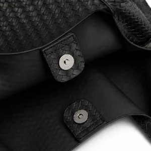 Λεπτομερές κοντινό πλάνο μαύρης πλεγμένης δερμάτινης τσάντας ώμου με μαγνητικό κούμπωμα.