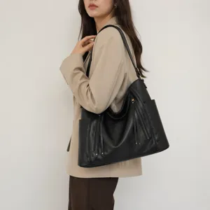 Black faux leather hobo shoulder bag detail view, featuring side pockets and zipper tassels.
