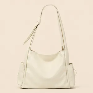 Cream leather shoulder bag detail, elegant knotted strap and side pockets design.