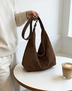 Nahaufnahme der braunen Wildleder Hobo Tasche zeigt weiche Textur und den breiten Riemen.