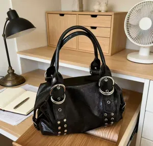 Schwarze Ledertasche mit Metallringen und Nieten, ideal für den Arbeitsweg und den Alltag.