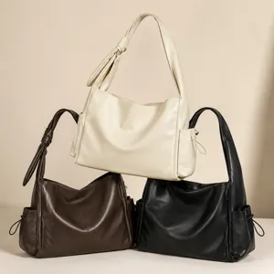 Detailed view of slouchy leather shoulder bags with knotted straps and side pockets in three colors.