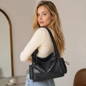 Close-up detail shot of the stylish black leather slouchy shoulder bag worn by model.