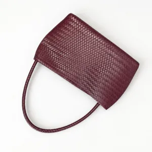 Woven leather shoulder bag detail, elegant burgundy texture and classic braided design.