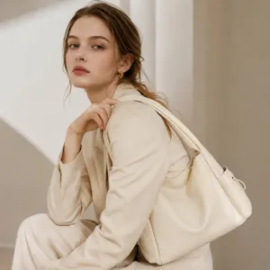 Detail shot of a chic beige shoulder bag worn by a model in a professional studio setting.