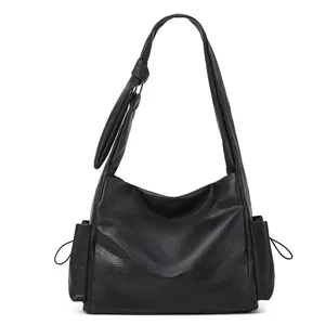 Black slouchy shoulder bag detail showing soft leather texture, side pockets, and pleated strap.