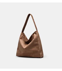 Suede shoulder bag detail shot, soft brown texture, minimalist underarm tote design.