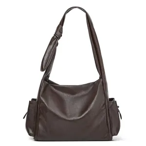 Dark brown leather hobo bag detail, featuring a stylish knotted strap and convenient side pockets.