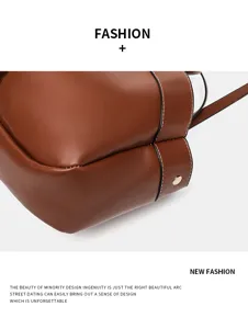 Nahaufnahme einer eleganten braunen Leder-Eimer-Tasche mit kontrastierenden weißen Nähten.