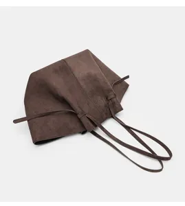 Dettaglio borsa tote in camoscio marrone, con consistenza morbida, doppi manici e stile.