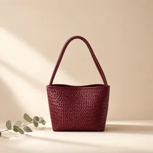Burgundy woven leather shoulder bag with chic bucket design and elegant vintage style appeal.