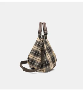 Detailed closeup view of the vintage plaid canvas shoulder bag with durable brown handles.