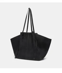 Dettaglio della borsa tote in camoscio nero, con soffietti laterali e manici lunghi.