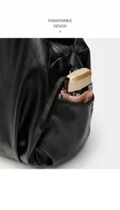 Detailaufnahme einer schwarzen weichen Lederhandtasche mit Seitentasche und Plissee.
