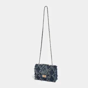 Detail view of the denim quilted chain shoulder bag, featuring raw edges and metal turn-lock.