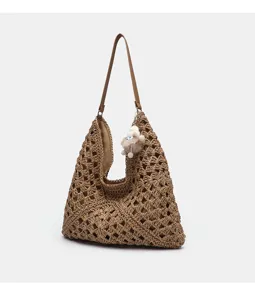 Detailansicht einer stylischen sommerlichen Stroh geflochtenen Schultertasche mit Anhänger.